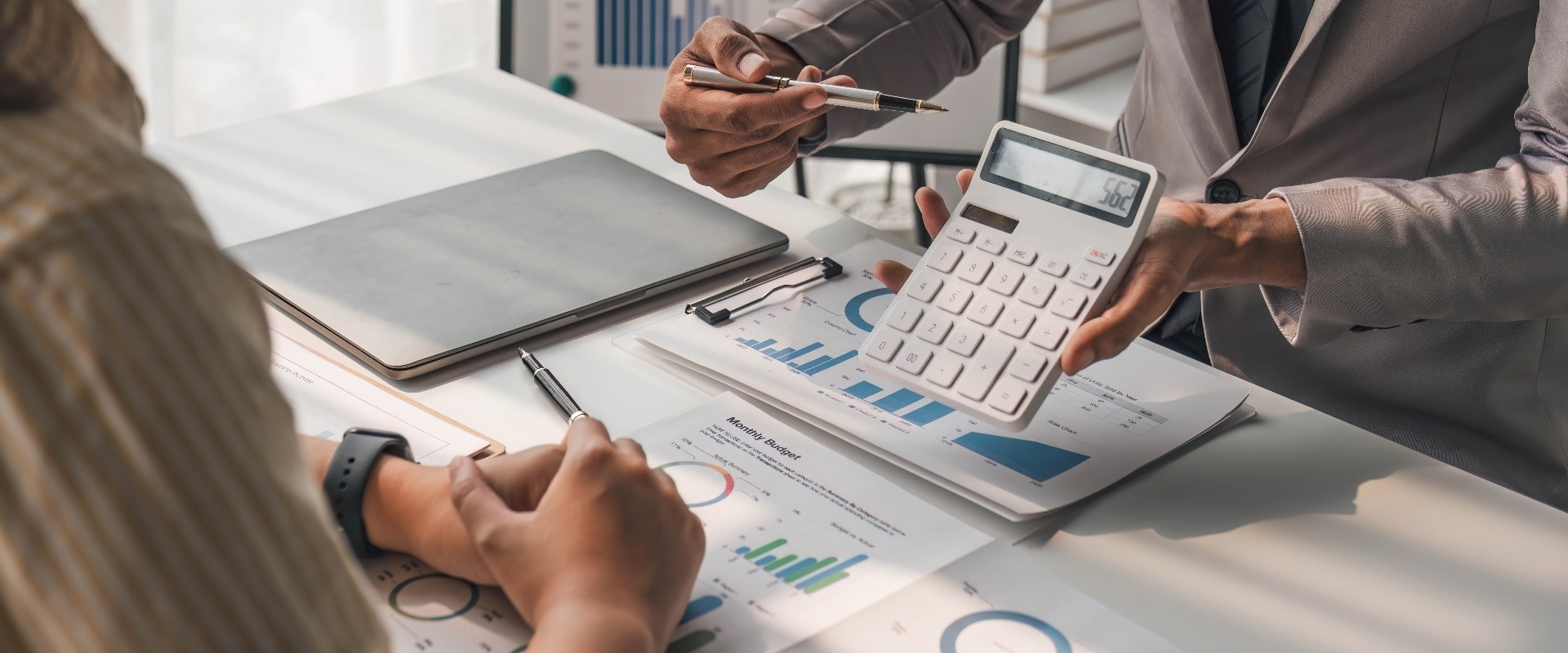 Two business people talk project strategy at office meeting room. Businessman discuss project planning with colleague at modern workplace while having conversation and advice on financial data report.